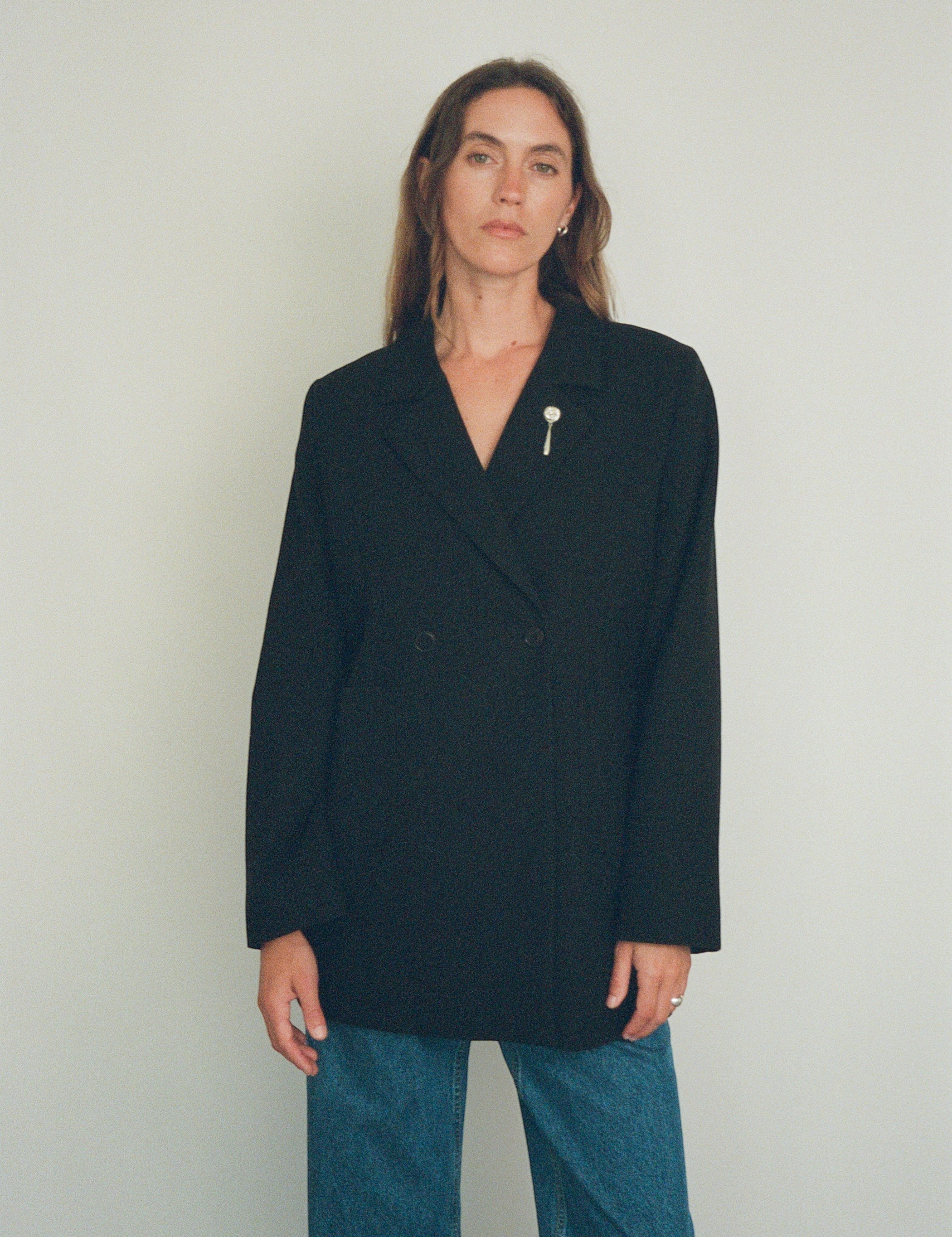 Model wearing a Sommer Tirza Brooch, a handmade sterling silver rose pin, on a black double-breasted blazer