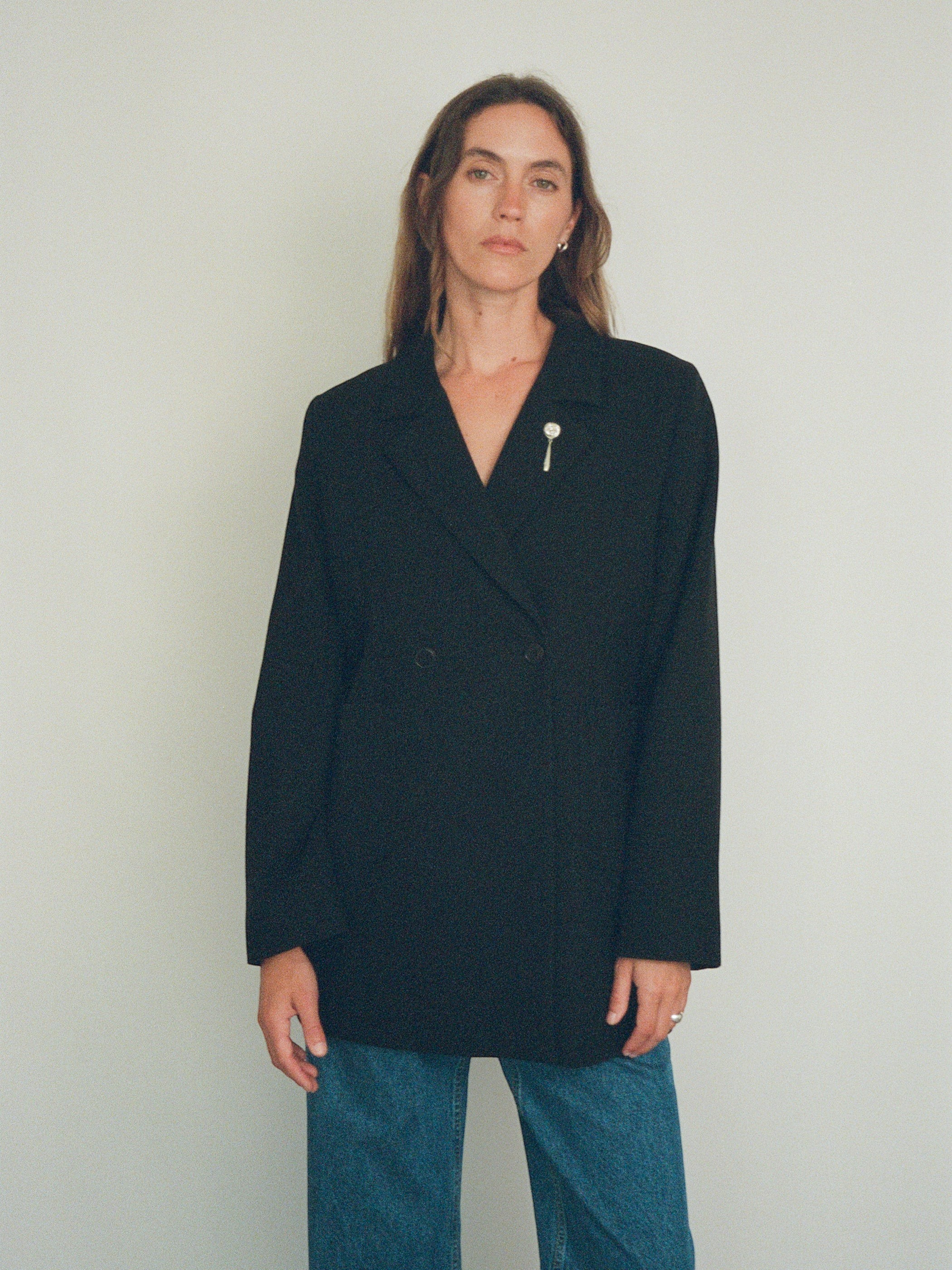 Model wearing a Sommer Tirza Brooch, a handmade sterling silver rose pin, on a black double-breasted blazer